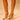 Close-up of a person wearing AZALEA WANG ESMARIA WHITE METAL EMBELLISHED PUMP stilettos with ankle straps and gold accents. Only the lower legs and feet in the faux patent leather heels are visible on a light surface.