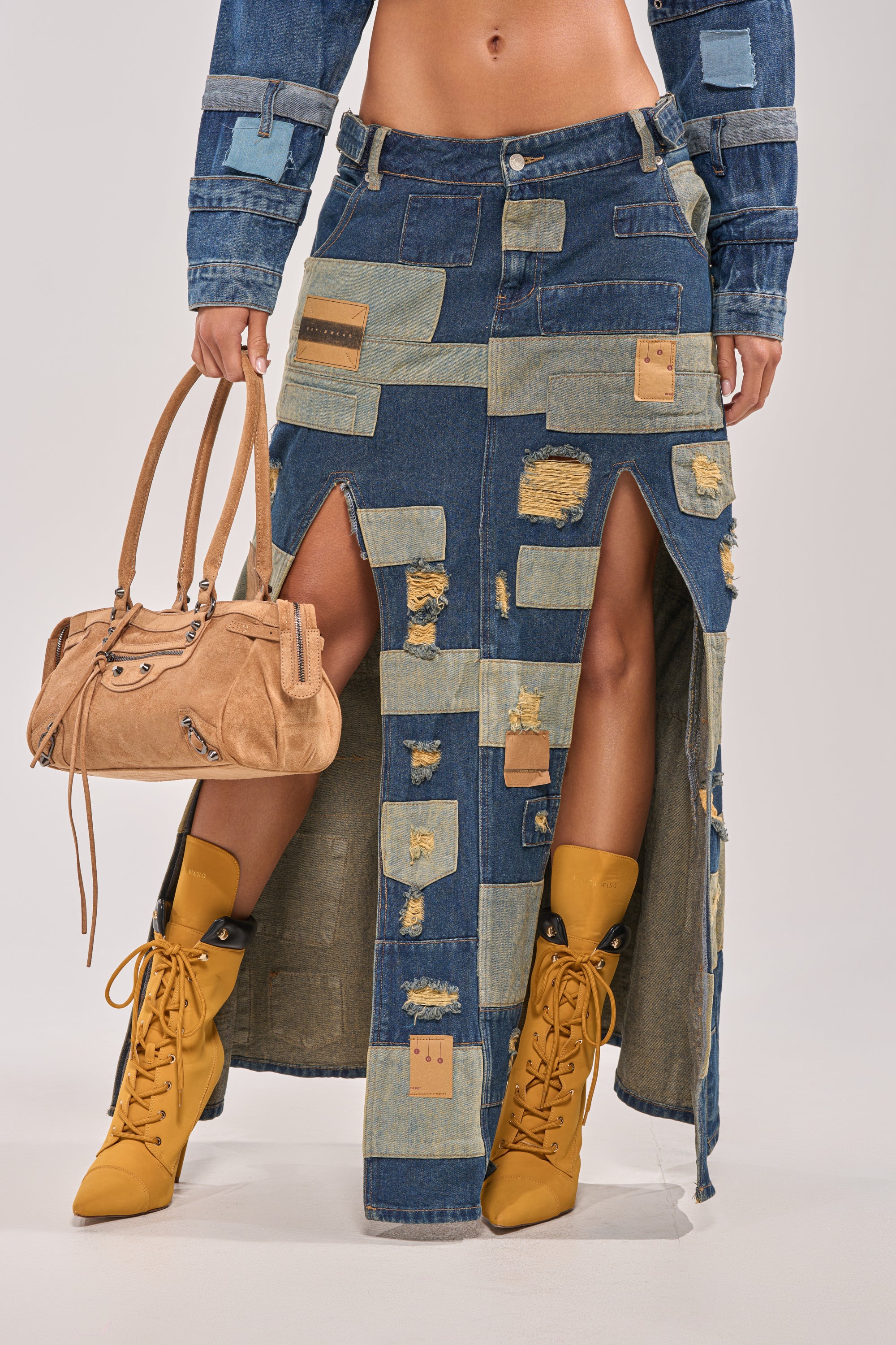 Rock streetwear vibes in the PATCH ME UP DENIM MAXI SKIRT, featuring patchwork and distressed details, paired with mustard yellow lace-up boots, a cropped denim jacket, and a tan handbag for festival-ready flair. 1