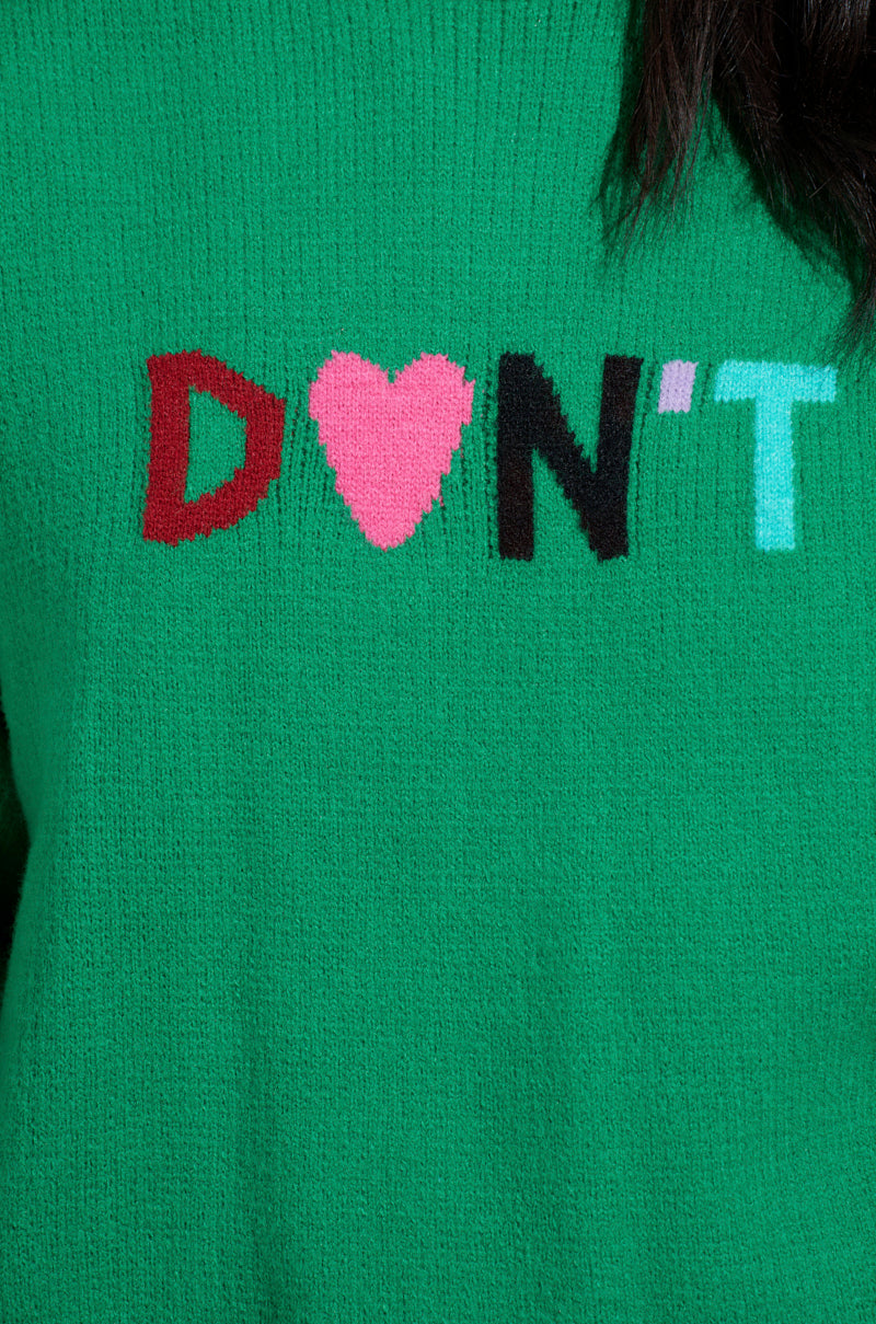 The AKIRA Label DONT DO IT SWEATER is a green oversized knit pullover with "DON'T" in red, black, and light blue. A pink heart replaces the "O," adding charm to the textured design.