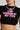 A person wearing the STOP LOOKING BABY TEE, an ultra-cropped black t-shirt featuring hot pink text saying "STOP LOOKING AT MY TITS," paired with a silver chunky chain necklace. The image emphasizes the upper body.