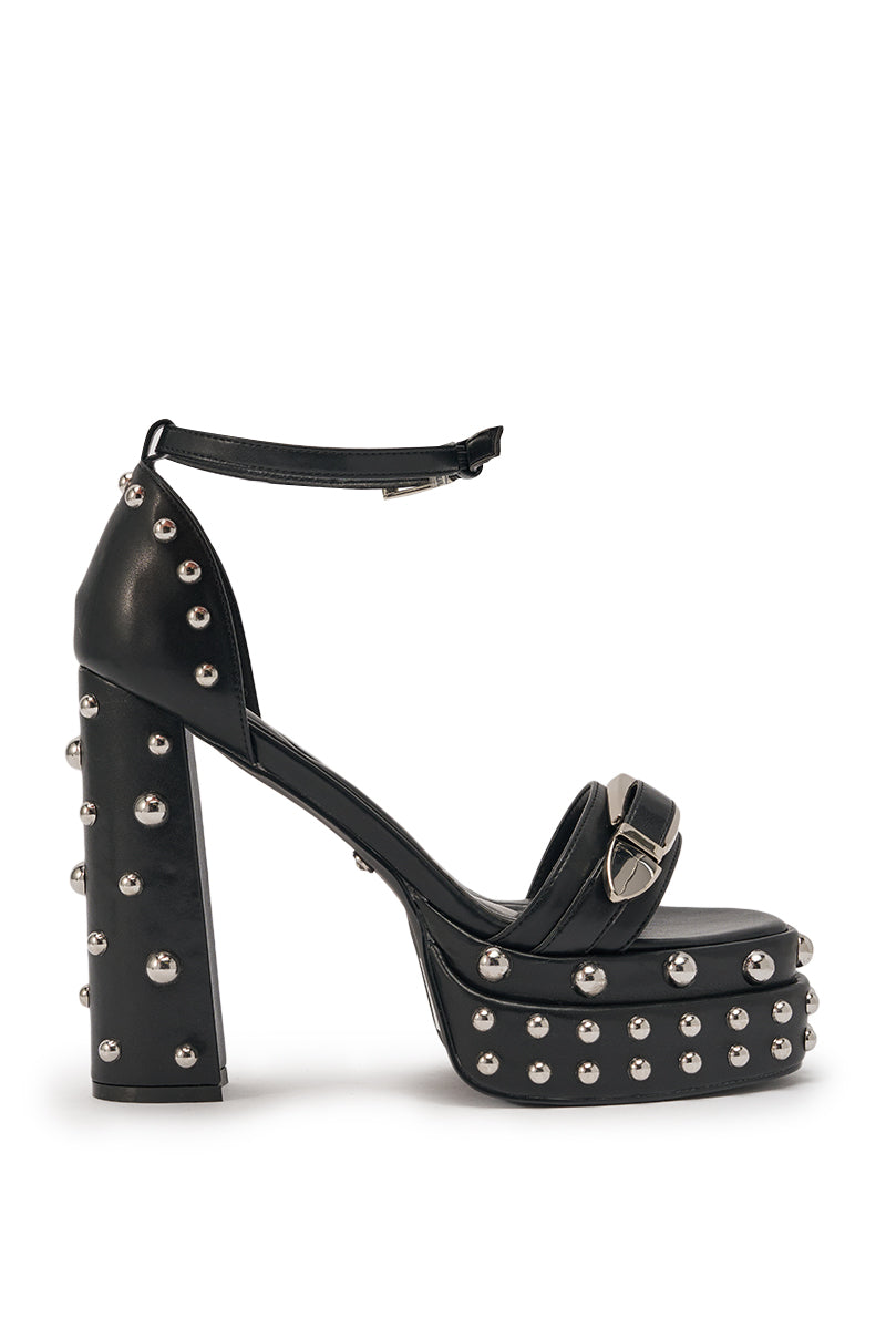 The AZALEA WANG EUGENIJA Black Chunky Embellished Studded Sandal is a faux leather platform heel with an ankle strap, silver stud accents on the heel, platform, and straps, plus a chunky heel and metallic front buckle. 3