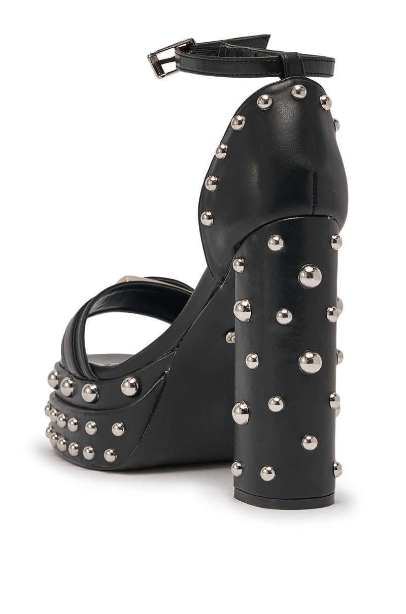 The AZALEA WANG EUGENIJA BLACK CHUNKY EMBELLISHED STUDDED SANDAL is a black faux leather platform sandal with an ankle strap, detailed with silver studs on the block heel, strap, and platform. 5