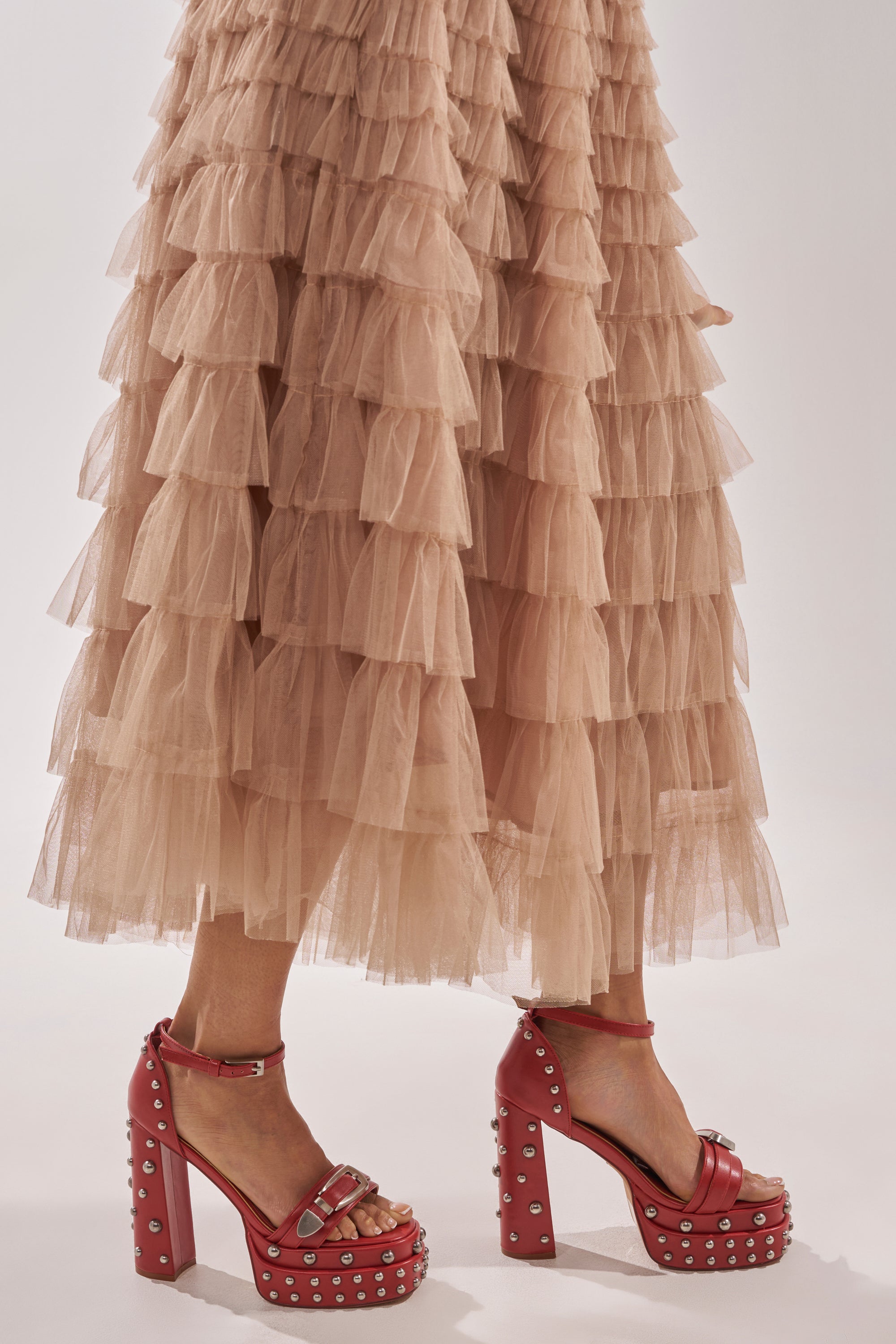 A person wearing a tiered ruffled beige tulle skirt and AZALEA WANG EUGENIJA Red Chunky Embellished Studded Sandals stands against a light background. 2