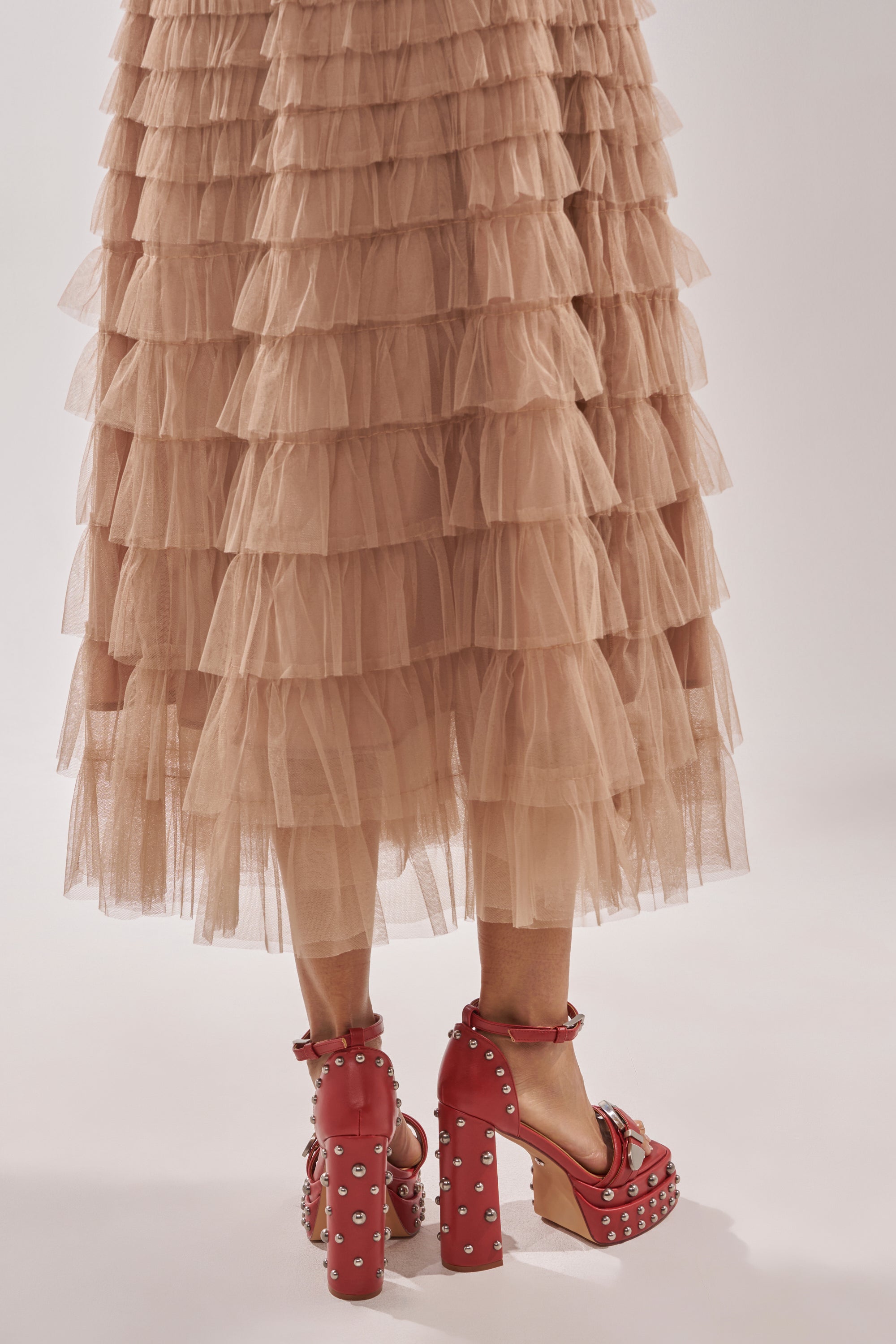 A person wearing a layered beige tulle skirt and AZALEA WANG EUGENIJA red chunky embellished studded sandals stands against a plain light background. 3
