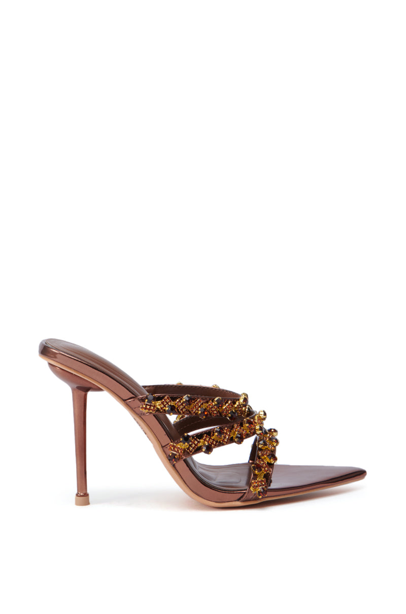 The AZALEA WANG EUREKA BRONZE EMBELLISHED STILETTO SANDAL features a faux leather upper adorned with sparkling strap details. This elegant shoe highlights an open pointed toe and a sleek stiletto heel, beautifully presented on a plain white background.