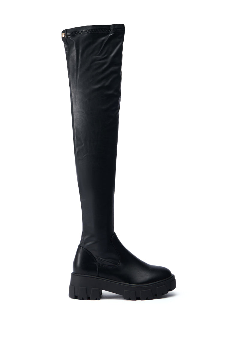 The AZALEA WANG EUREVA BLACK FLAT BOOT, featuring a chunky sole and a faux leather finish, is displayed against a plain white background.
