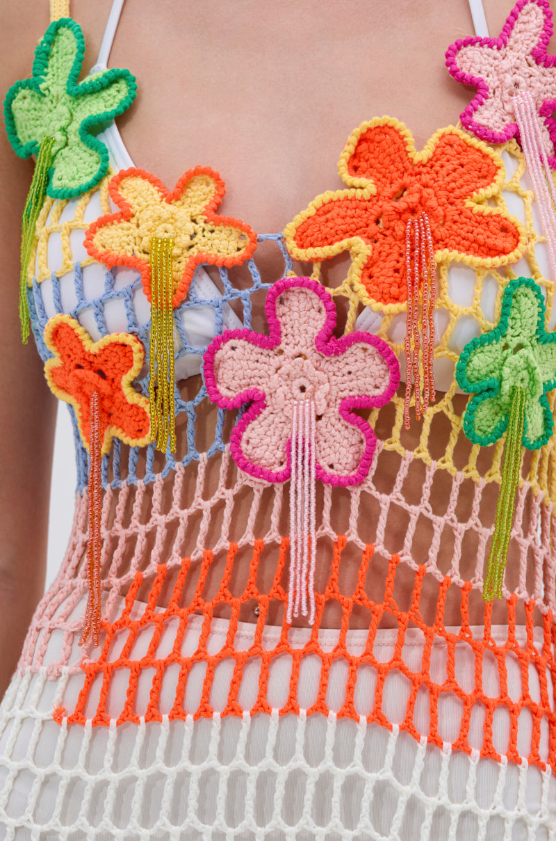 Close-up of the BEACHIN IT CROCHET BEADED MAXI DRESS, featuring large floral patterns in orange, pink, yellow, and green with beaded fringes. The open crochet design is layered over white for a breezy effect.
