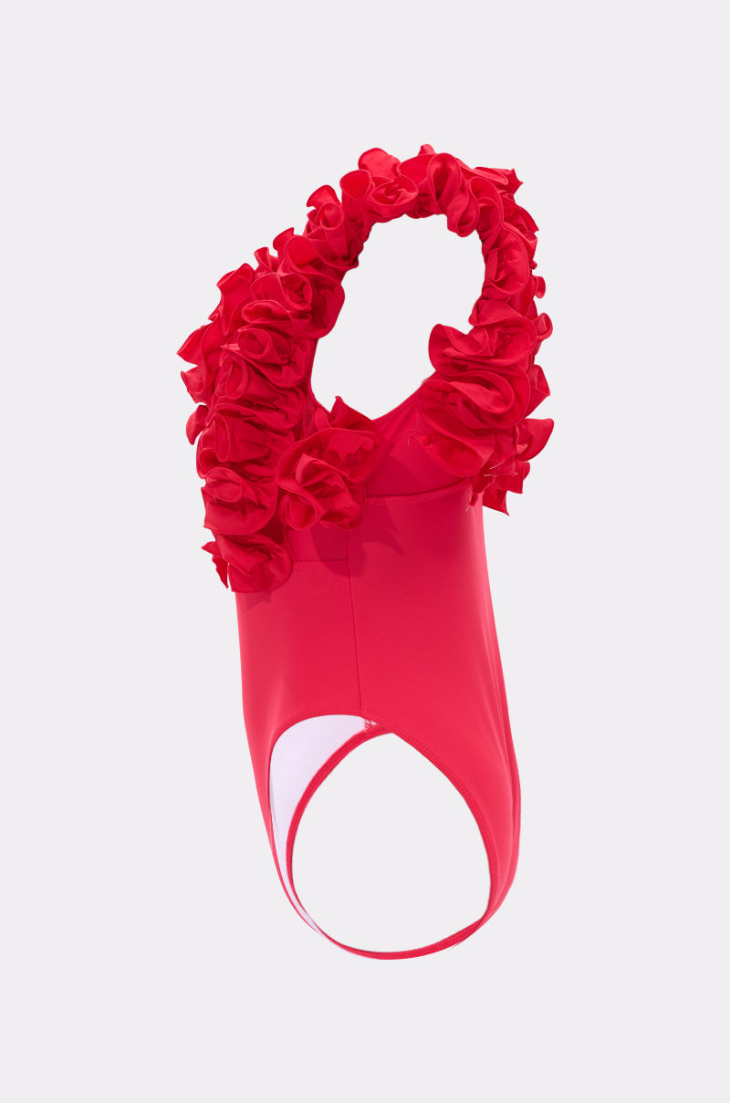 The LUXE LIFE RUFFLE SWIMSUIT is a bright red, sleeveless one-piece with a circular waist cutout and bold ruffles at the neckline and arms, shown on a plain light background.