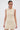 A woman with dark hair pulled back wears the FEELIN SWEET KNIT SWEATER DRESS WITH PEARLS, a cream-colored, curve-hugging mini dress with textured knit details, standing against a plain white background and gazing to the side.