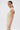 A woman with straight brown hair in a low ponytail wears the FEELIN SWEET Knit Sweater Dress with Pearls and white flower-shaped earrings, posing sideways against a plain white background.