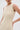 A woman poses with one hand on her hip against a white background, wearing the FEELIN SWEET Knit Sweater Dress With Pearls—a sleeveless, textured cream dress. Only the lower part of her face is visible as her head turns slightly.