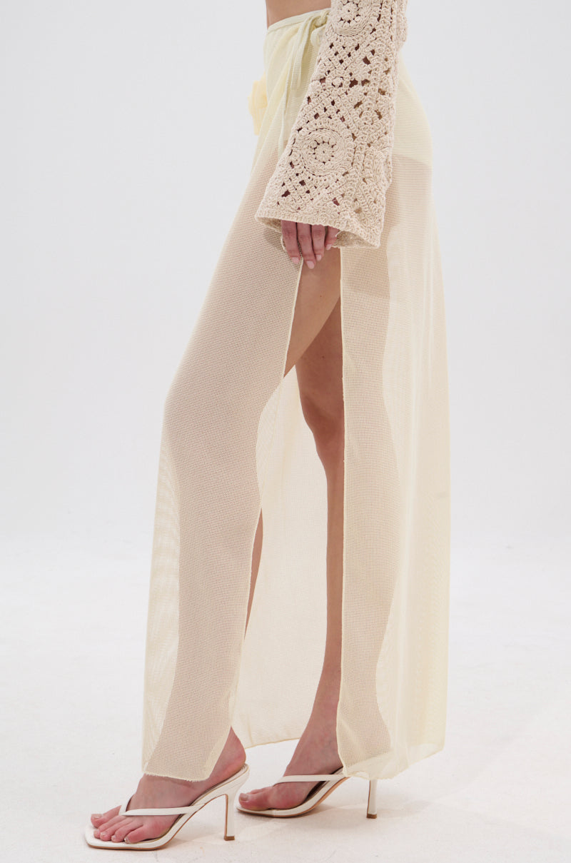 A person models the sheer, light yellow CROCHET BEAUTY COVER UP SKIRT with a high slit and crocheted sleeve, paired with white heeled sandals—ideal for a seamless transition from beach to brunch—against a white background. 3