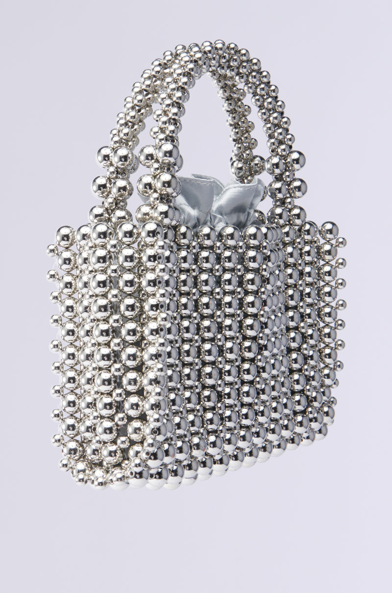 Introducing the IM SO IT GIRL BEADED PURSE: a hot-girl handbag crafted from metallic silver beads, featuring a shimmering beaded handle and a soft silver fabric insert, all set against a plain light gray background.