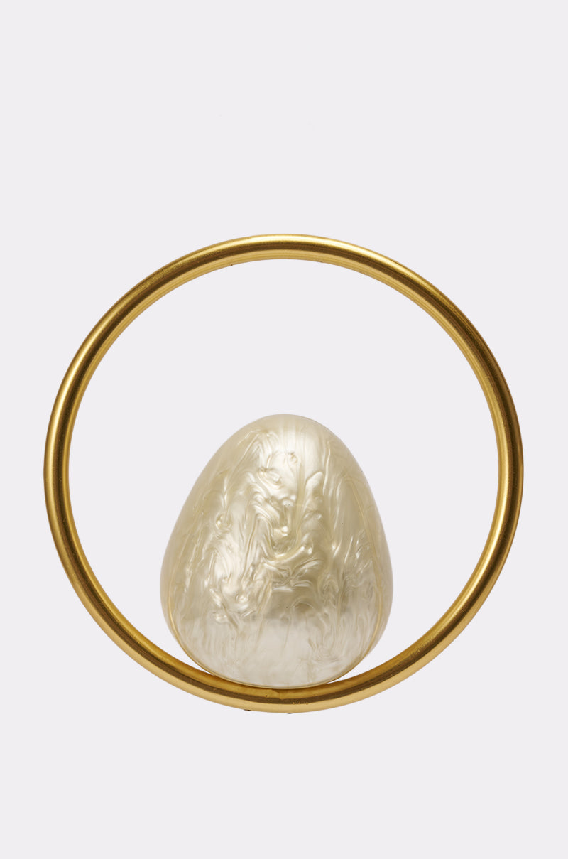 The ON MY MIND BAG, a pearly white, textured, egg-shaped acrylic handbag with a simple upright gold-tone handle, is displayed against a plain light gray background. 1
