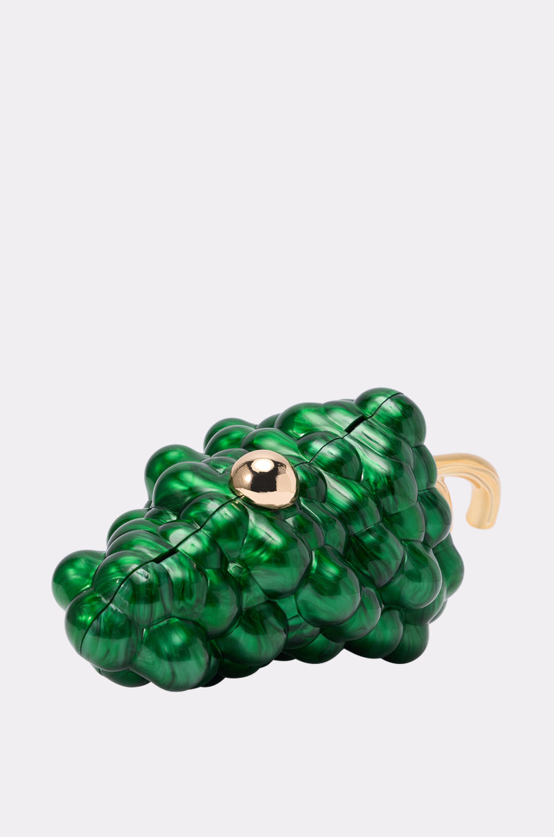 The I FEEL GRAPE CLUTCH is a shiny green grape-shaped bag with a marbled finish, gold stem and circular clasp, plus a detachable gold chain strap, shown on a light gray background. 2