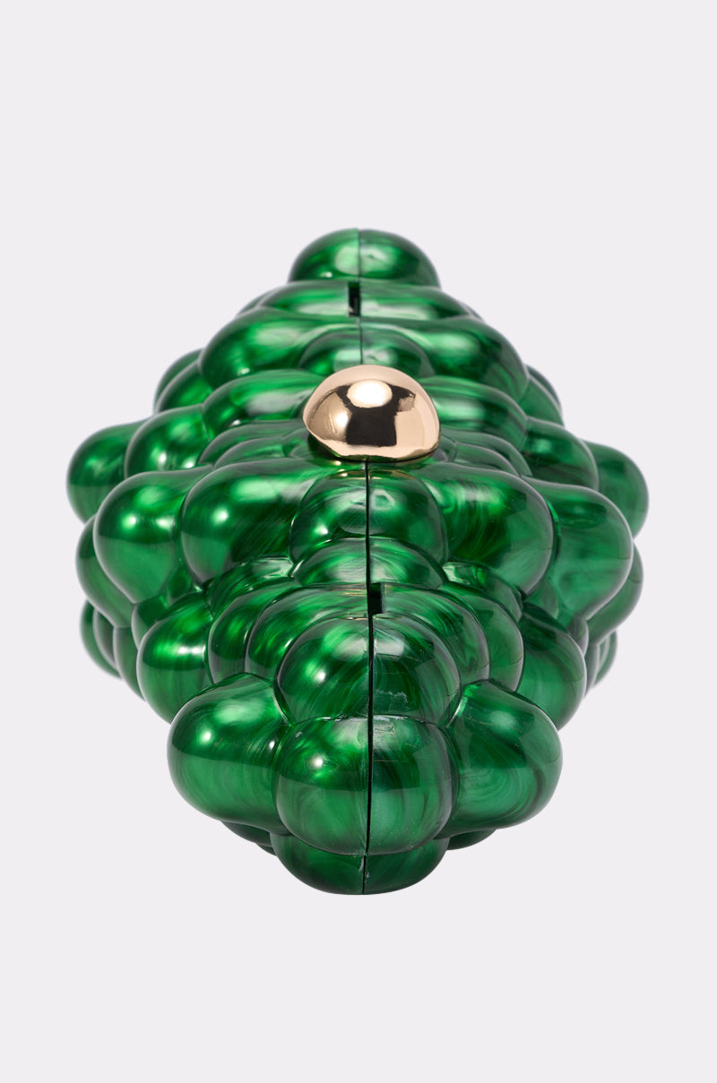 The I FEEL GRAPE CLUTCH is a green acrylic bag with a marbled high-shine finish, bubble-like sculptural details, and a round gold clasp, set against a plain light gray background. 5