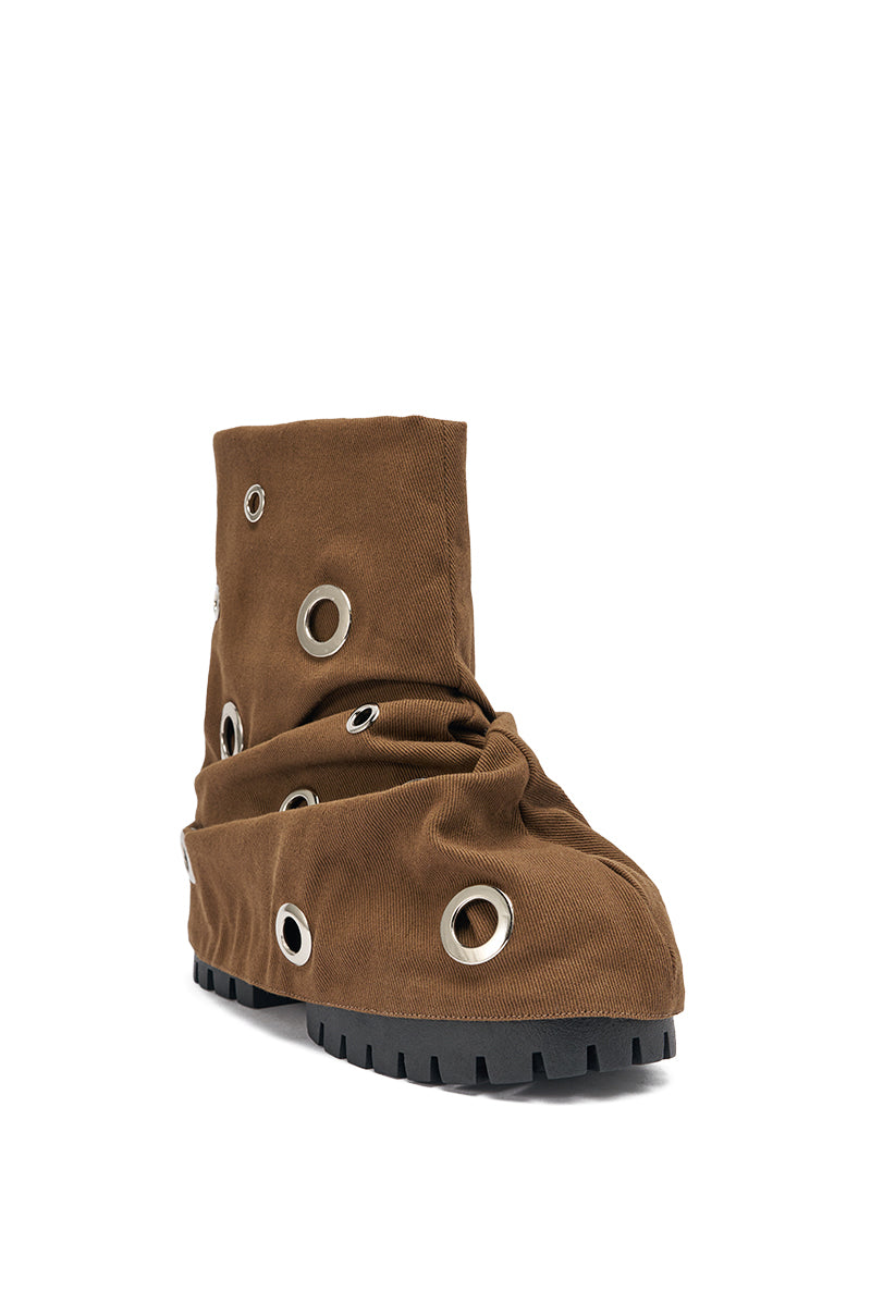 The AKIRA GOLD FABLE BROWN GROMMET EMBELLISHED FLAT BOOTIE features a brown upper with large metal eyelets and a rugged black sole, creating a distinctive and bold look. 4