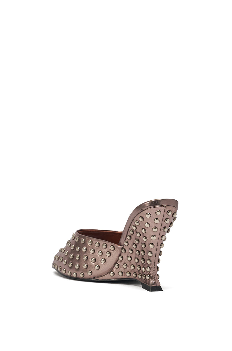 The AZALEA WANG FABRON PEWTER EMBELLISHED WEDGE SANDAL is a metallic brown faux leather mule featuring a moderately high wedge heel and rows of round silver studs, with the heel also adorned in dazzling embellishments. 6
