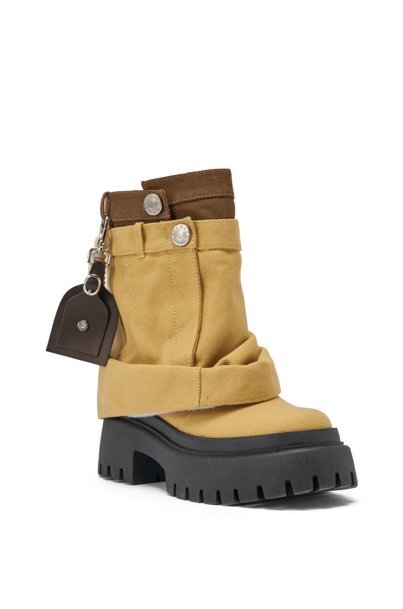 The AKIRA GOLD FAE TAN BOOTIE is a tan and brown ankle boot with a chunky lug heel, thick black treaded platform sole, decorative straps and buttons, plus a small brown keychain pouch on a metal loop. 5
