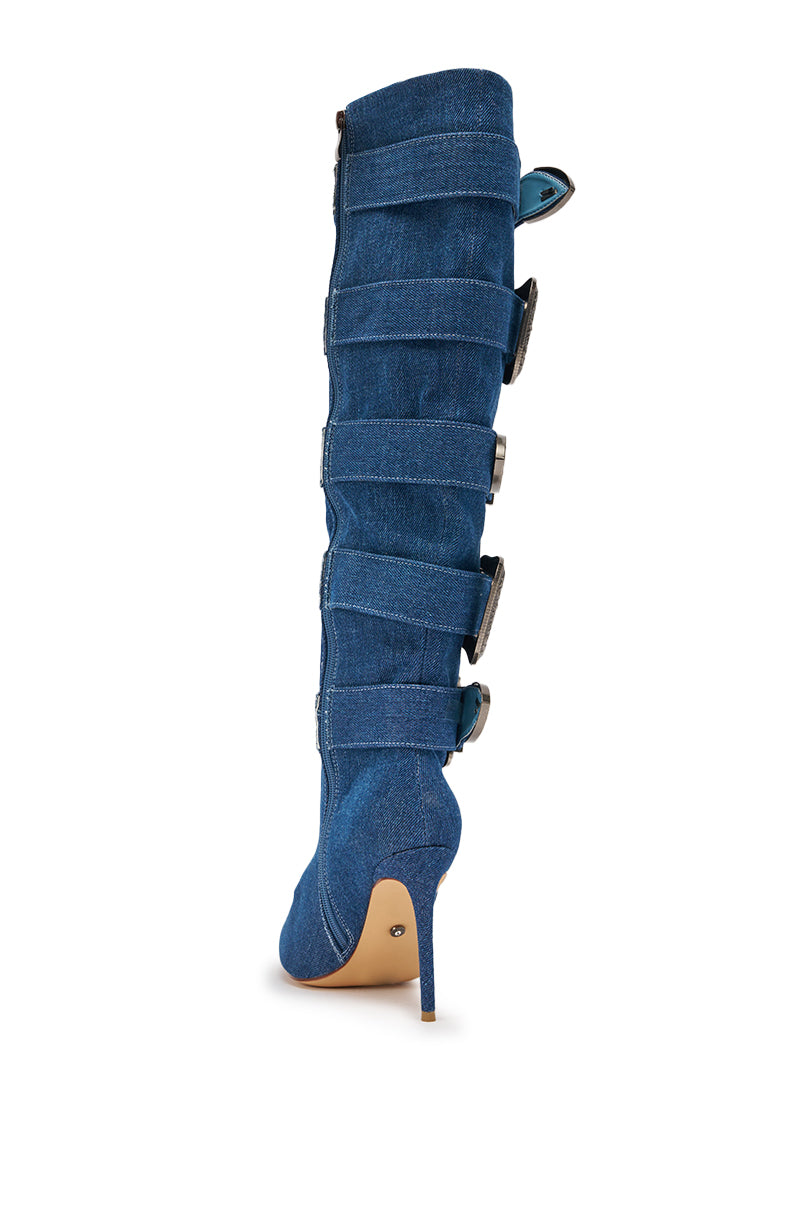 Side view of the AKIRA GOLD FALLON DENIM BUCKLE EMBELLISHED STILETO BOOT, a knee-high denim boot with cowgirl-inspired style, detailed with multiple wide horizontal straps and shiny buckle fastenings along the outer side. 6
