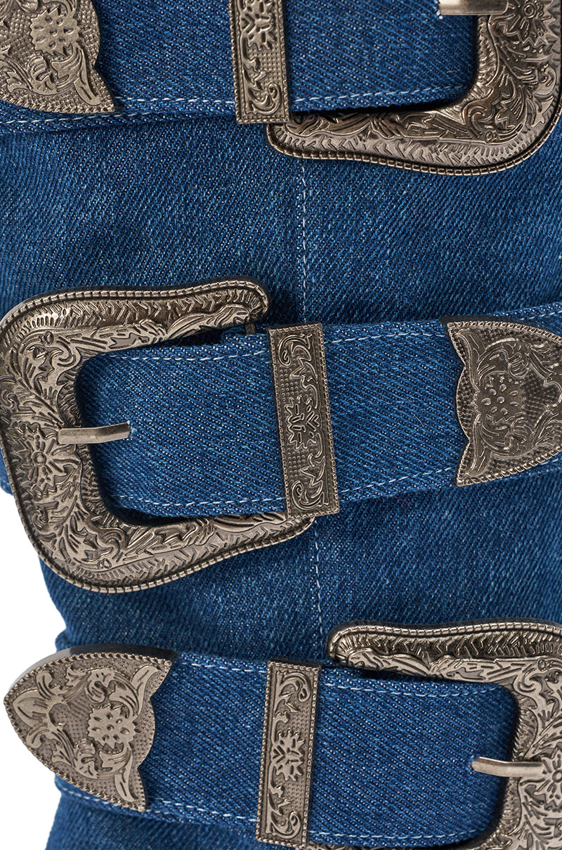 Close-up of blue denim fabric with three ornate silver buckles, inspired by cowgirl-couture details on the AKIRA GOLD FALLON DENIM BUCKLE EMBELLISHED STILETTO BOOT. 7