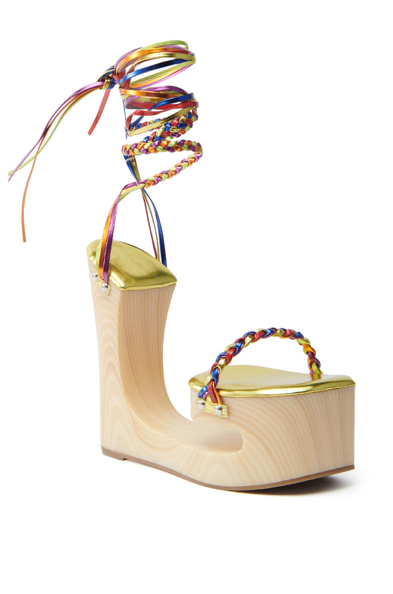 Explore the AZALEA WANG FANTASA RAINBOW STRAPPY WEDGE SANDAL, featuring a chunky wooden platform, multicolored braided straps with an ankle wrap, a shimmering gold footbed, and an artistically sculpted heel to elevate any look.