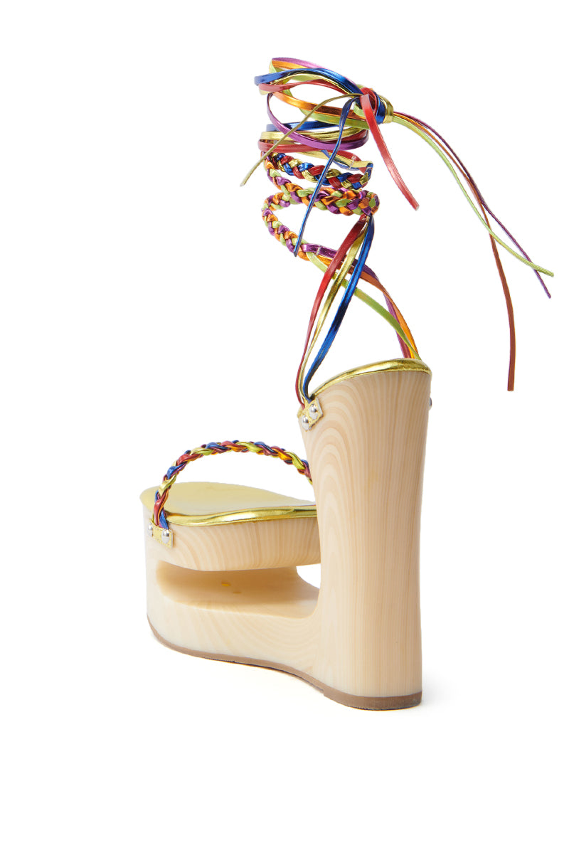 Introducing the AZALEA WANG FANTASA RAINBOW STRAPPY WEDGE SANDAL, a chic wooden platform with colorful braided straps around the ankle. Featuring a chunky wedge heel and natural wood sole, its glossy finish adds elegance, making it perfect for any occasion.