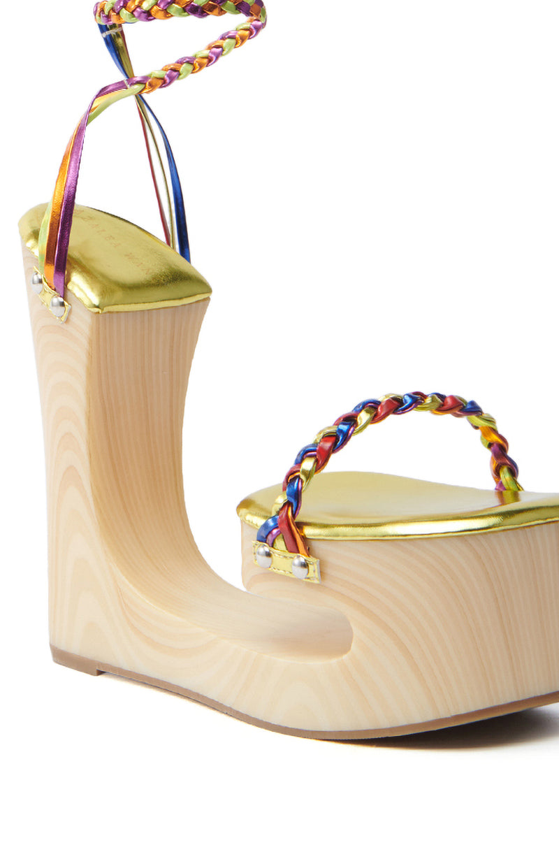 Meet the AZALEA WANG FANTASA RAINBOW STRAPPY WEDGE SANDAL: a stunning high wooden platform with a curved wedge design, gold accents, braided rainbow straps, and an ankle wrap. This sandal is bold and eye-catching with its chunky heel and modern artistic flair.