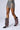 A model showcases a fashion-forward look featuring a metallic, reflective mini skirt paired with the AZALEA WANG FARLEY EMBELLISHED BOOT. These black pointed-toe boots are adorned with intricate red, white, and silver beadwork in a circular pattern. The boots sport a mid-calf shaft and kitten heel, made even more stylish by their faux suede upper. The plain white background highlights the outfit details perfectly.