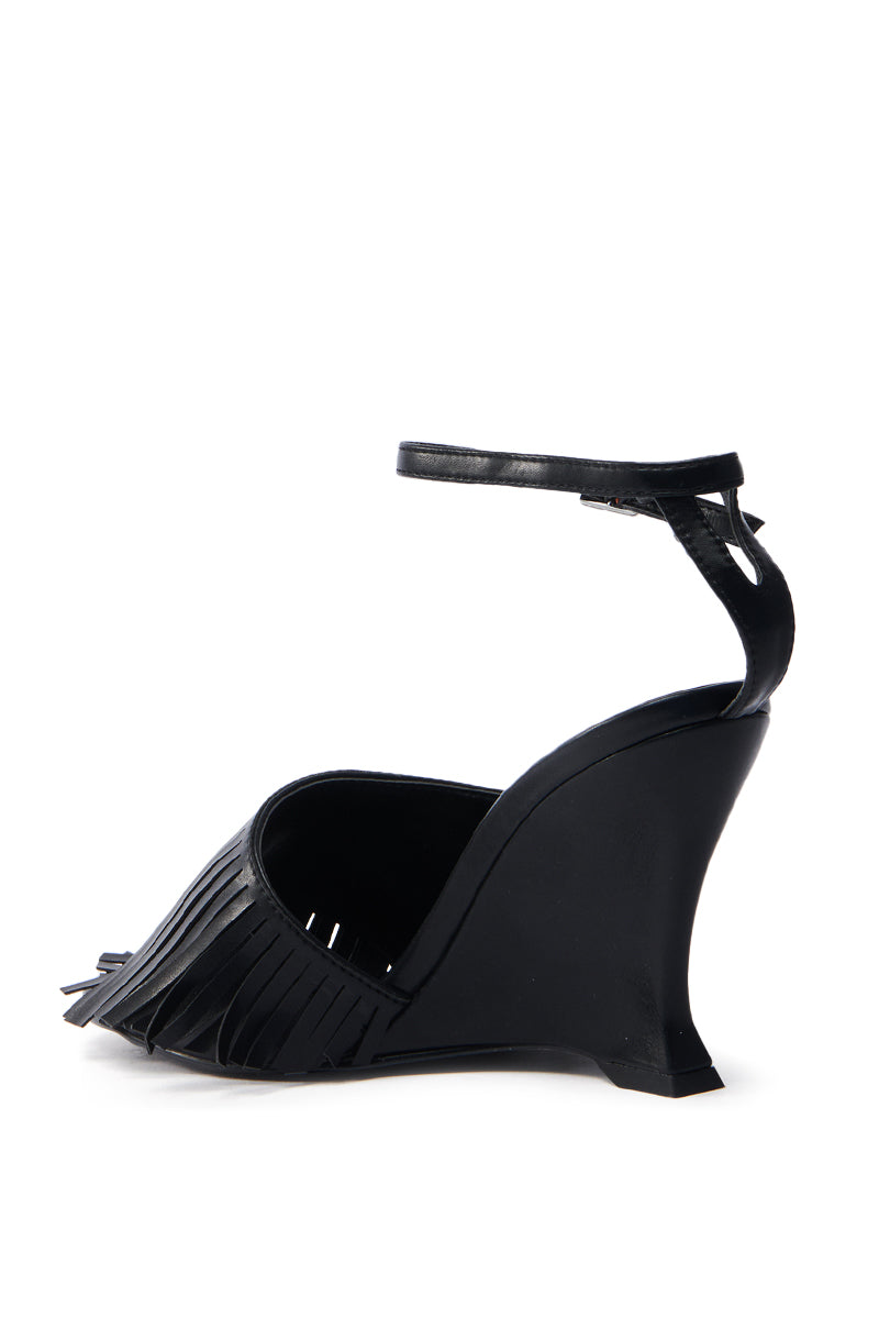 The AZALEA WANG FASCIA BLACK FRINGE WEDGE SANDAL is crafted from vegan leather, featuring a curved heel, fringe detailing, an ankle strap, and an open-toe design for a chic and modern look.
