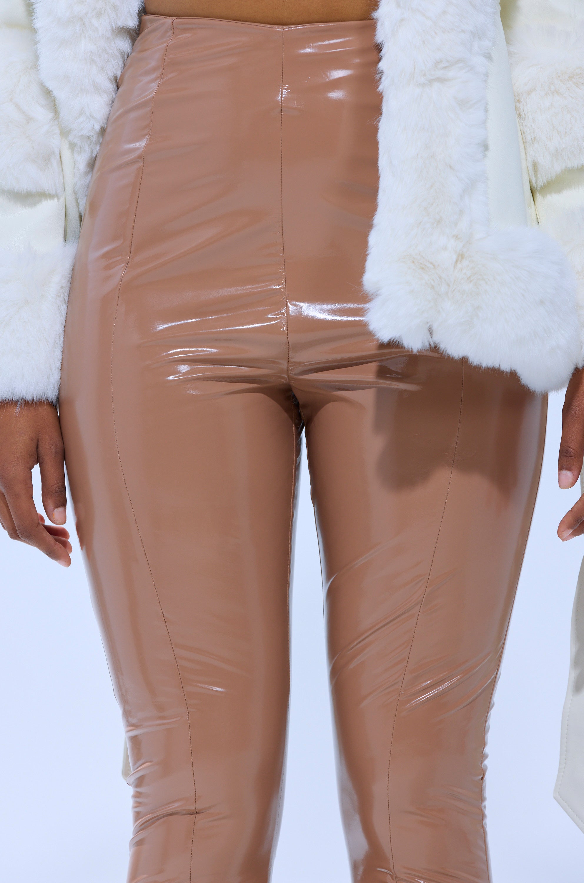 A person is shown from waist to mid-thigh wearing the GET GROOVY FAUX LEATHER SKINNY LEGGING and a white faux fur jacket against a light background. 7