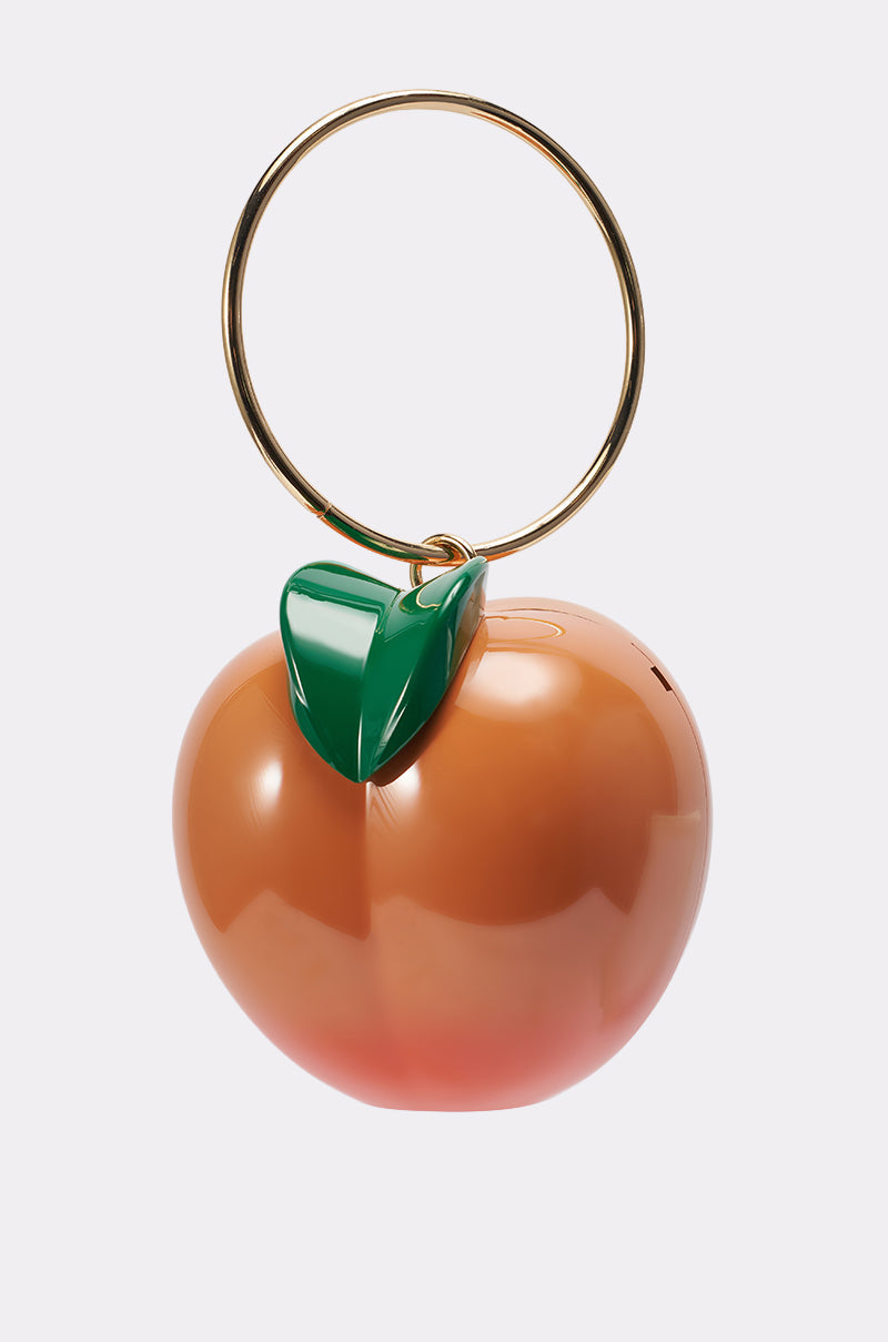 The FEELIN PEACHY BAG is a shiny, peach-shaped purse featuring a gold circular handle, green leaf accent on top, and a removable crossbody strap, displayed against a plain white background. 1