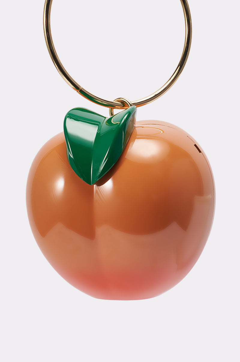 The FEELIN PEACHY BAG is a glossy, peach-shaped purse with a green leaf accent and a large gold circular handle, making it stand out against a plain white background. 2