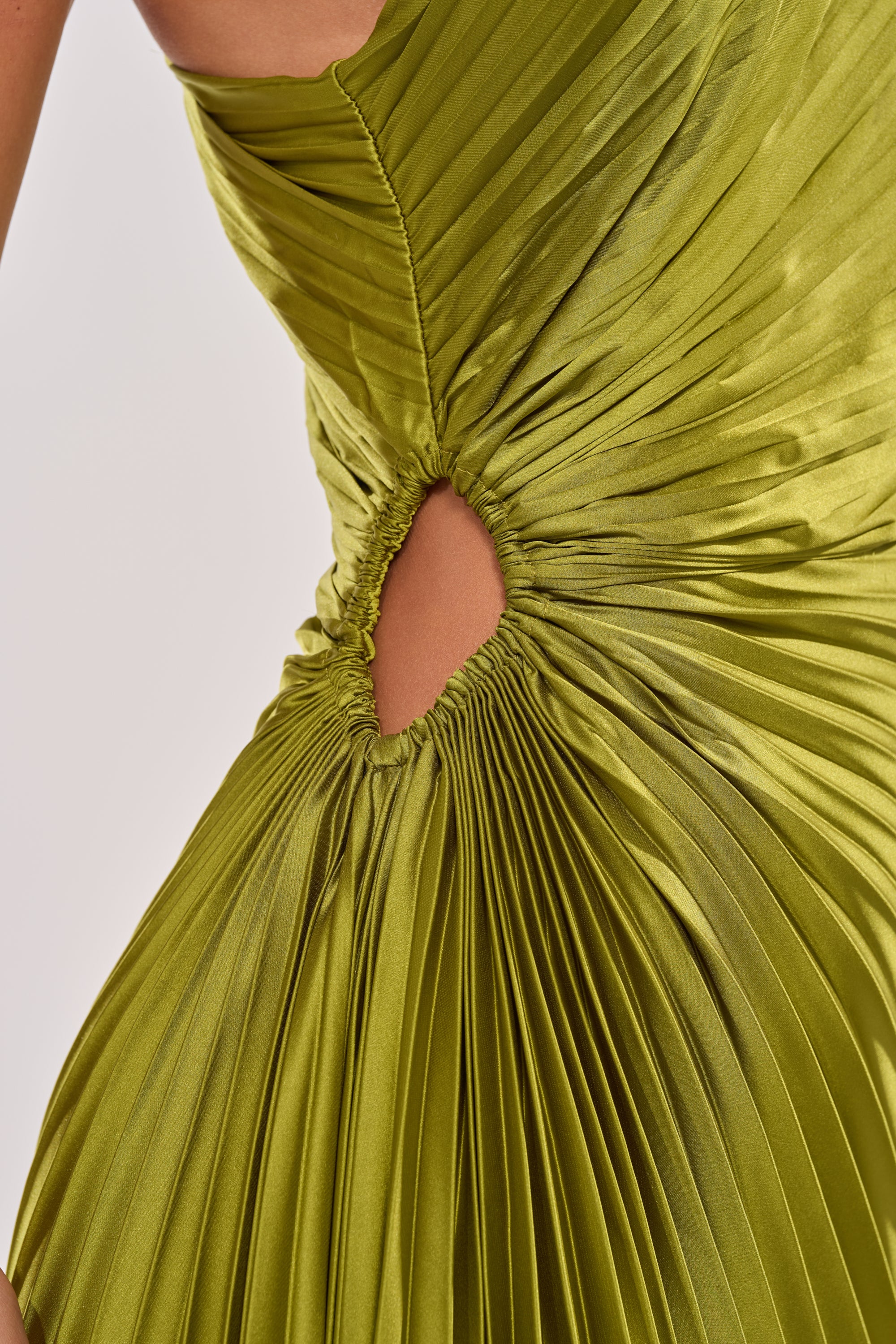 Close-up of the MIDNIGHT MAVEN SLEEVELESS MAXI DRESS IN GREEN, a shiny chartreuse pleated satin formal dress with a small circular waist cutout and gathered fabric detailing. 8