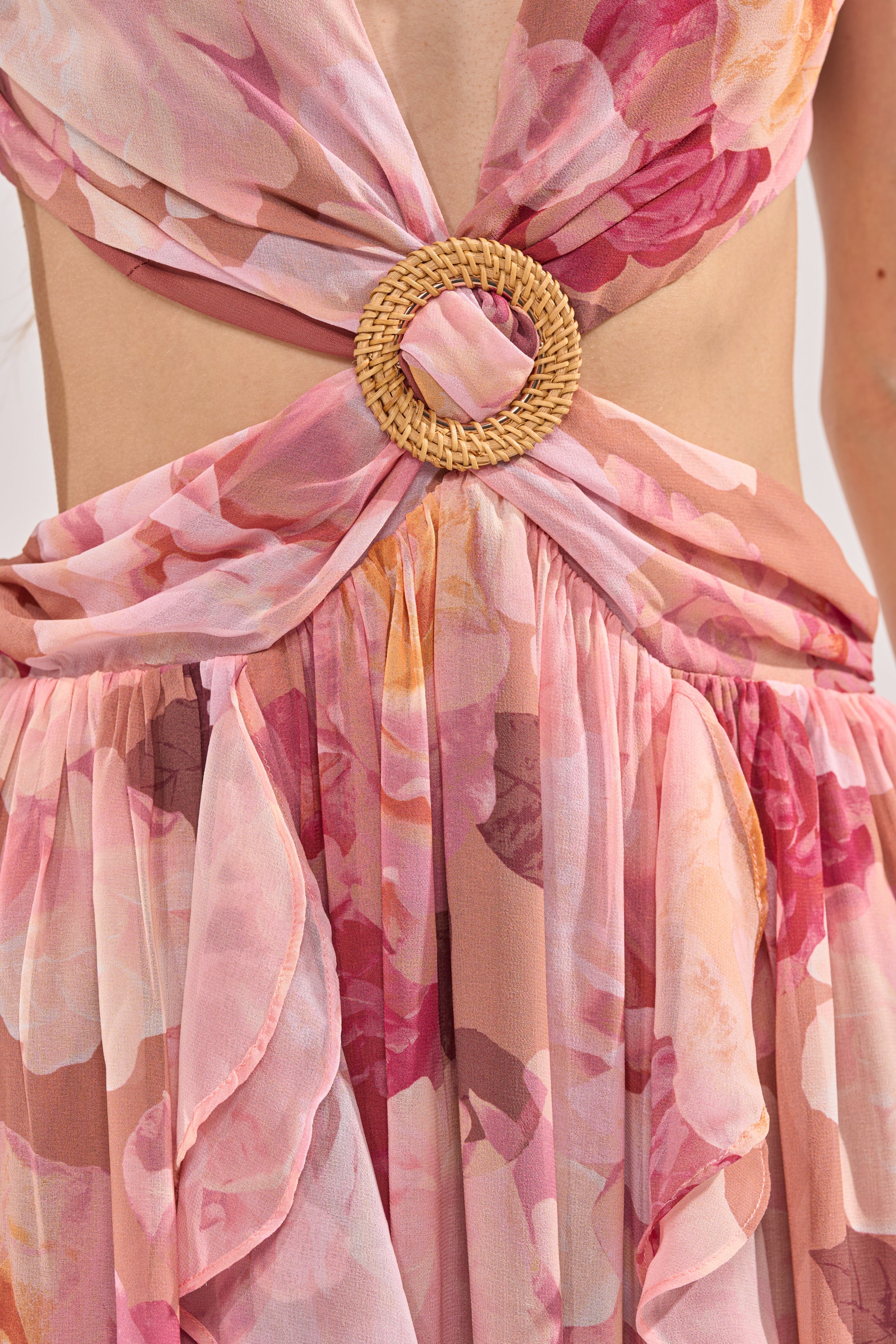Close-up of the LOVE YOU LATER FLORAL MAXI DRESS: pink chiffon with rose prints, a deep neckline, gathered waist, circular woven belt buckle, cut-out details, and sheer fabric—ideal for spring occasions. 6