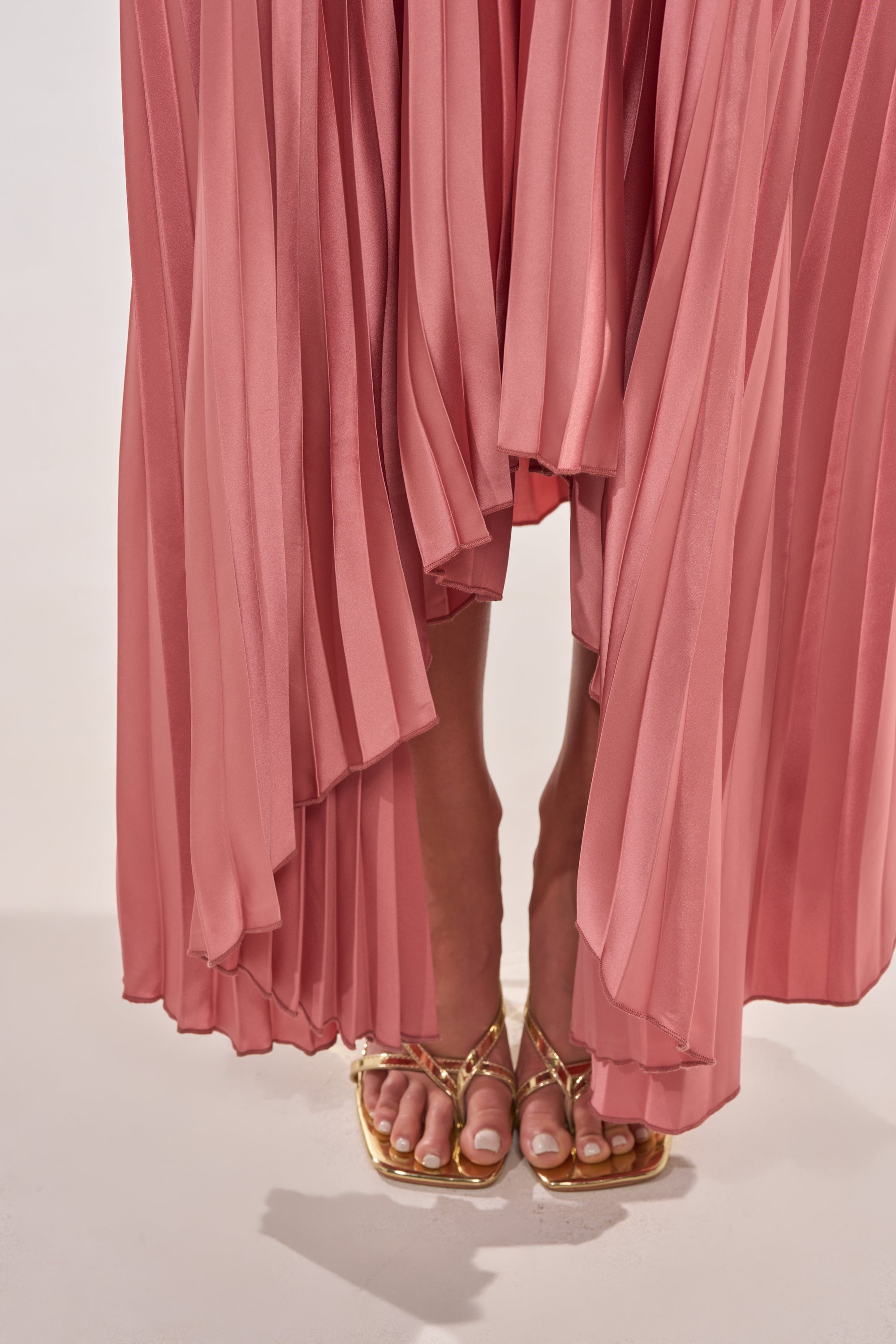 A person stands on a light surface with only their feet and lower legs visible, wearing gold strappy sandals and the EMERALD DREAM SLEEVELESS MAXI DRESS IN PINK. 6