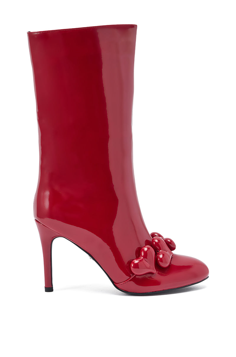 The AZALEA WANG FEDELE RED PATENT HEART EMBELLISHED BOOTIE is a shiny, knee-high stiletto boot featuring three heart-shaped accents on the toe, shown against a white background.