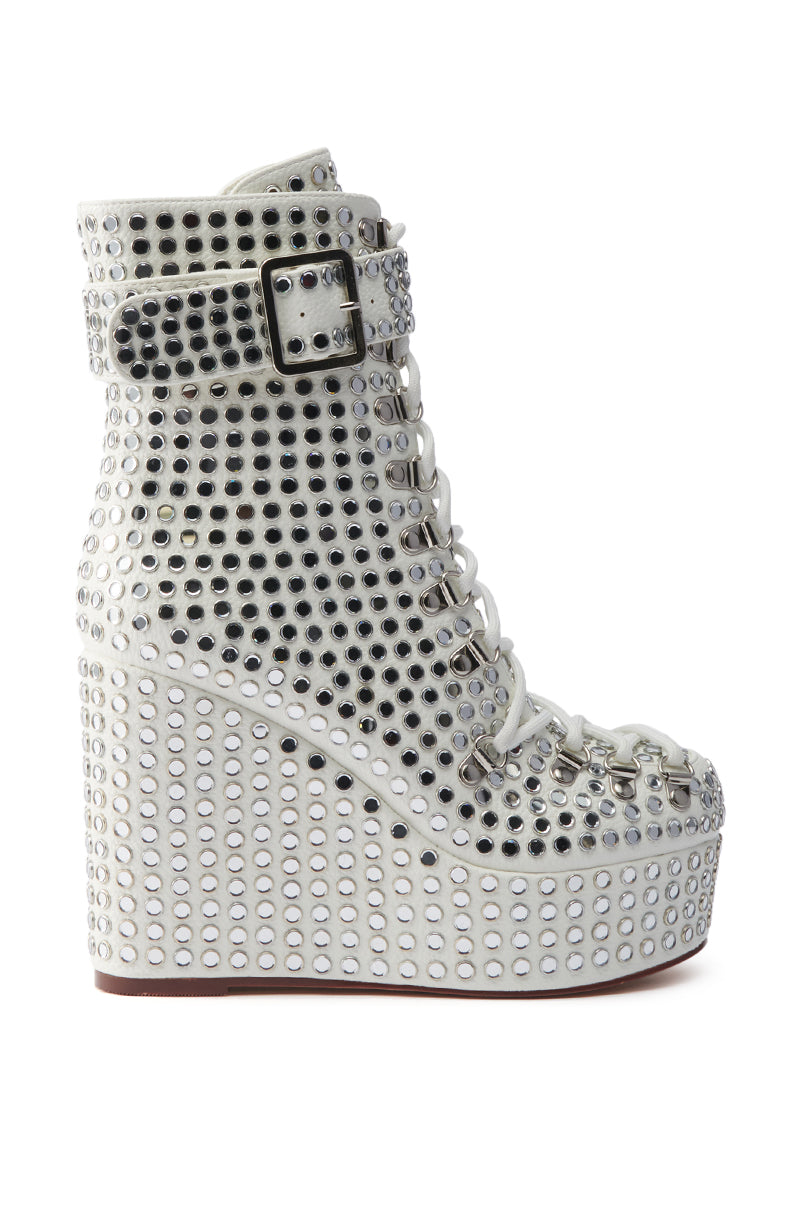 The AZALEA WANG FERDY WHITE PLATFORM EMBELLISHED BOOTIE features a white wedge heel, lace-up front, ankle strap, and a rhinestone-studded upper with shiny silver studs in rows for a bold, edgy look.