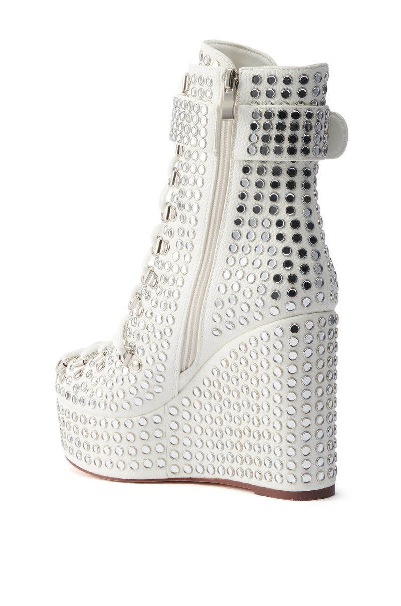 The AZALEA WANG FERDY WHITE PLATFORM EMBELLISHED BOOTIE features a wedge heel, open toe, lace-up front, side zipper, and a rhinestone-studded upper for extra shine.