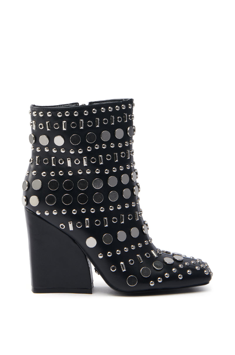 The AZALEA WANG FLETCHER BLACK SILVER METAL BOOTIE is a vegan leather ankle boot with a chunky block heel, featuring shiny silver studs and circular accents for a striking look.