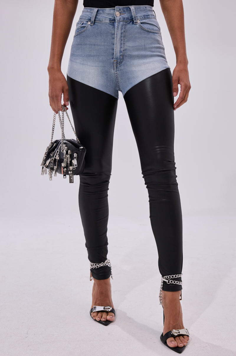 Wearing FLEX FIT EXTREME STRETCH HIGH WAIST SKINNY JEANS WITH FAUX LEATHER, a denim top, black handbag with chains, and black open-toe heels featuring chain ankle straps.