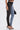 A woman wears the FLEX FIT EXTREME STRETCH HALF AND HALF PU HIGH WAIST SKINNY JEAN, featuring black faux leather on one leg and blue stretch denim on the other, styled with heeled sandals and a small black handbag.