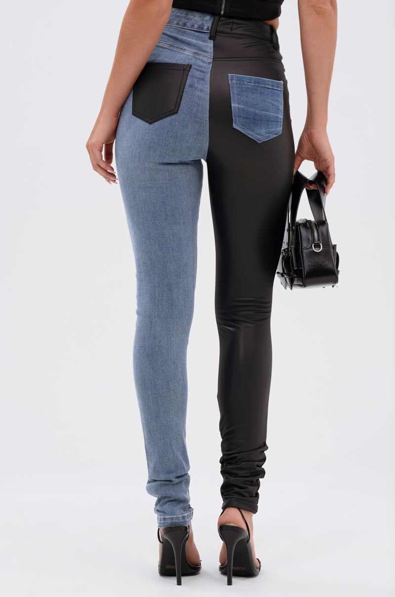 Wearing the FLEX FIT EXTREME STRETCH HALF AND HALF PU HIGH WAIST SKINNY JEAN—featuring one leg in stretch denim and the other in black PU—a person, seen from behind, carries a small black handbag.