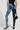 The individual is dressed in FLEX FIT EXTREME STRETCH HIGH WAIST SKINNY JEANS with a unique half-and-half PU design. One leg is crafted from blue denim, while the other features black faux leather. They accessorize with a black textured handbag and wear black studded high heels, all set against a light-colored background.