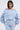 A woman with straight dark hair models the FLORAL LIFE OFF THE SHOULDER BLOUSE and matching high-waisted pants, adorned with a delicate floral pattern—ideal for a chic spring outfit. She poses against a plain light background.