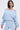 A woman with straight dark hair wears the FLORAL LIFE OFF THE SHOULDER BLOUSE and matching high-waisted pants in a light blue and white floral print, creating a chic spring look against a plain background.