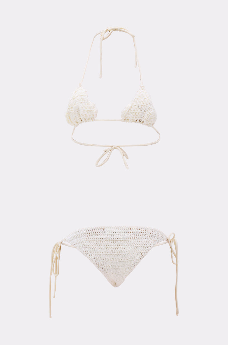 The CROCHET BEAUTY SWIMSUIT is a cream crochet set with a halter-neck triangle top and side-tie bottoms in a boho-chic bikini style, showcased against a plain white background.