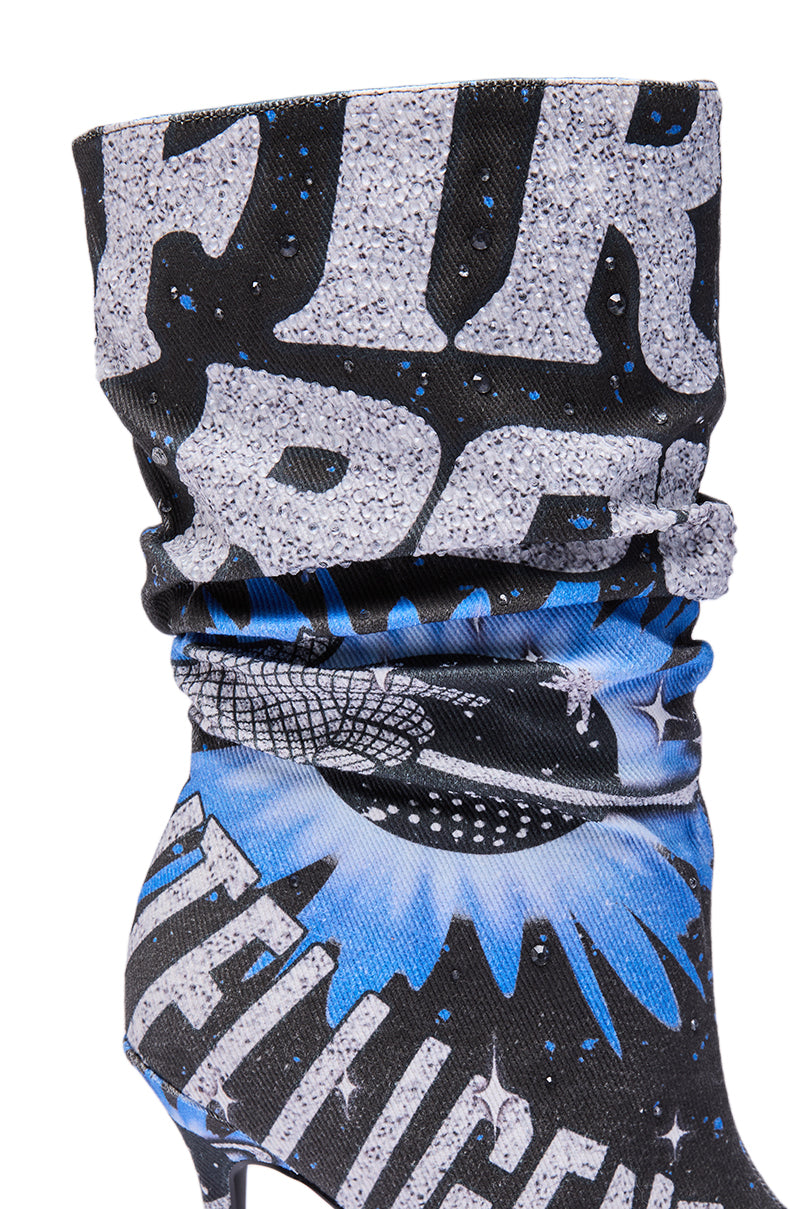 A close-up of the AKIRA GOLD FORMIDABLE BLACK MULTI ABSTRACT OPEN TOE BOOTIE, showcasing a black bootie with a glittery comic-style design, bold white letters, blue accents, and a sparkling disco ball graphic.