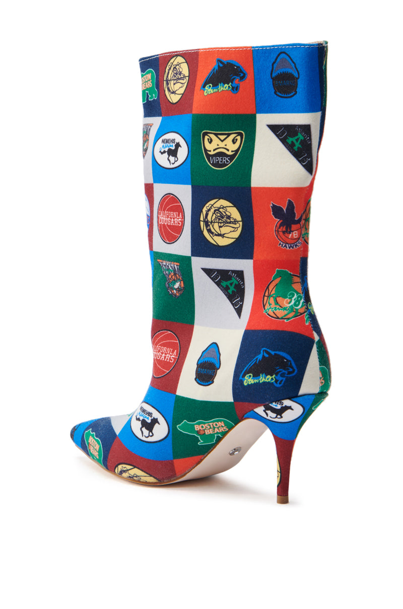 Introducing the AZALEA WANG FOUL MULTI SPORTY BOOTIE: a sporty-chic high-heeled boot with colorful patchwork sports logos and mascots. Its pointed toe and slender heel feature a vibrant colorblock pattern in red, blue, and white squares.