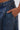 Close-up of a manicured hand resting in the front pocket of IZZY RELAXED DENIM jeans, showcasing detailed stitching and textured fabric.